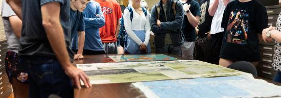 Group of students looking at world maps on a table