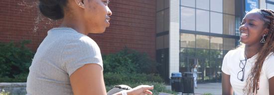 Two female African American students talking outside