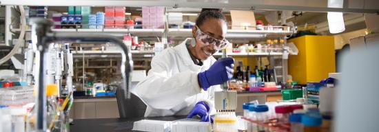 Female pharmacy student in a lab coat testing out pharmaceutical substances