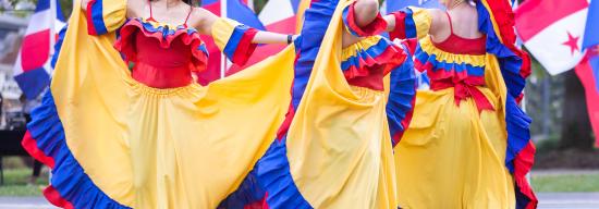 Latinx females wearing colorful clothing while dancing at a Latinx celebration