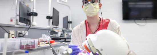 Female student dentist practicing on a fake patient