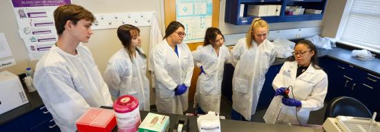 Group of students in their lab coats and their professor