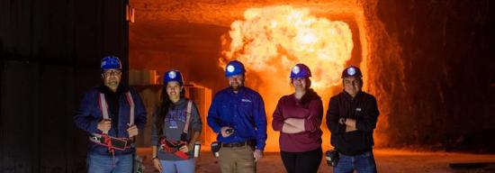 Mining Engineering students with a blast going off in the background.