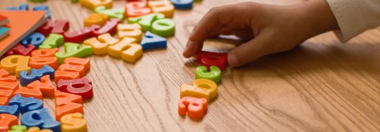 Child playing with lettered blocks on a table