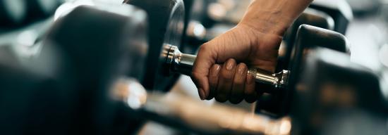 Hand grabbing a dumbbell in a row of dumbbells