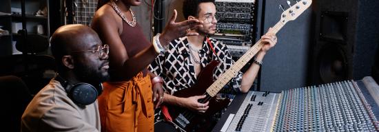 Three people in a music studio in discussion about work
