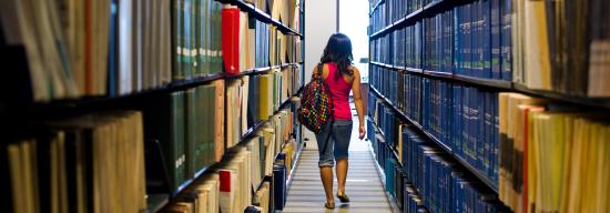 Female student walking through an aisle of books