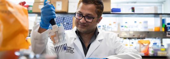 Male in a white lab coat manipulating substances