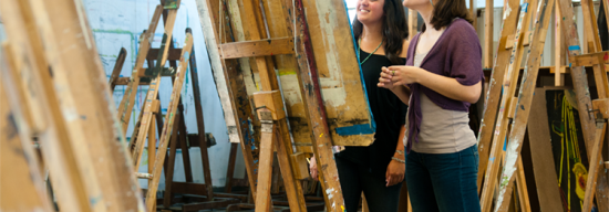 Female students painting on a big canvas in an art studio