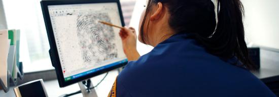 Policewoman observing a fingerprint on a computer screen